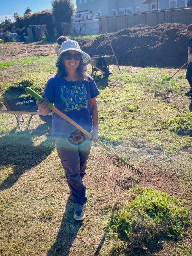 Garden board member, Shireen Agherdien, working a rake.